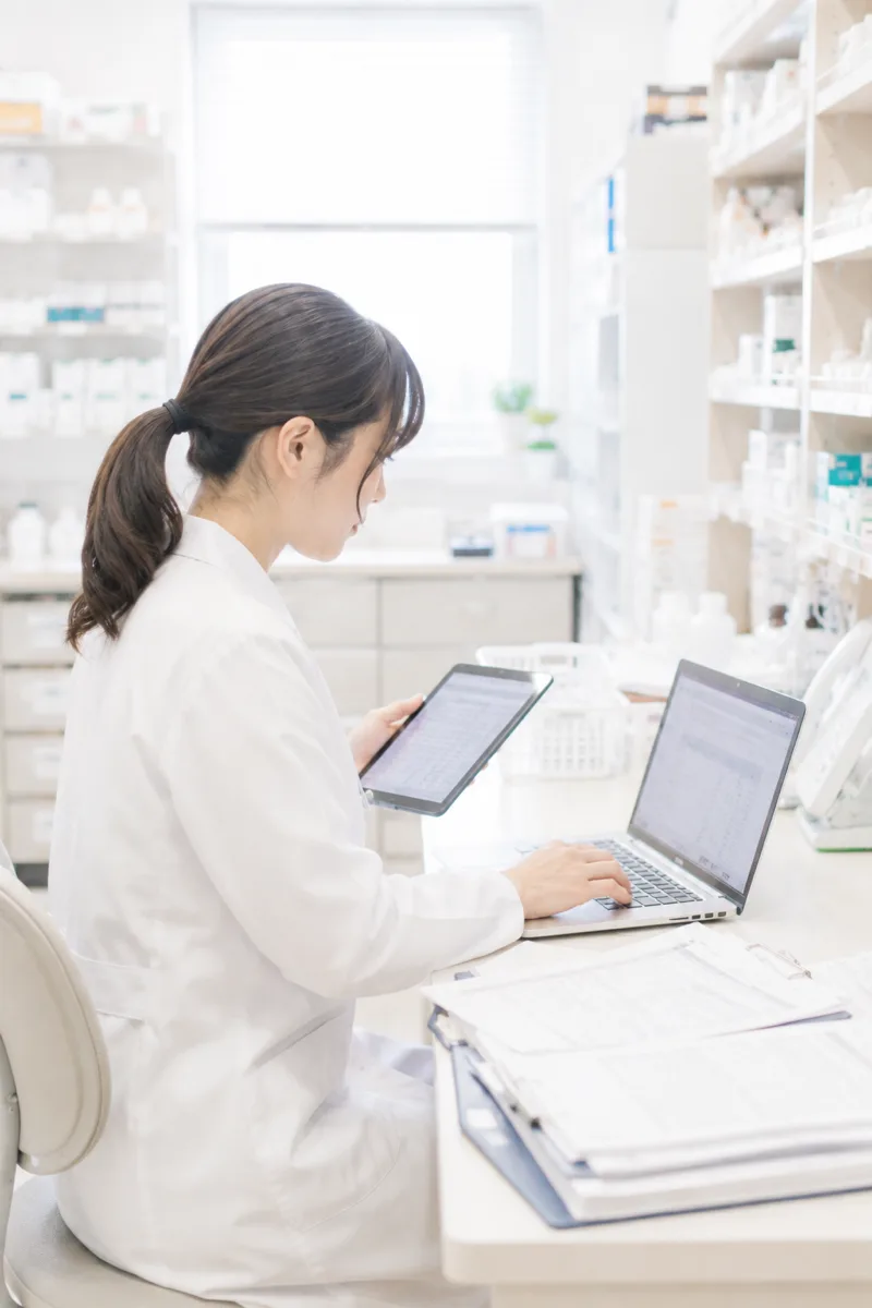PCとタブレットで事務作業をする薬剤師